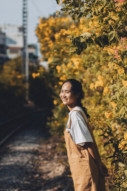 白色礼服的妇女站立在黄色叶子附近的 · 免费素材图片