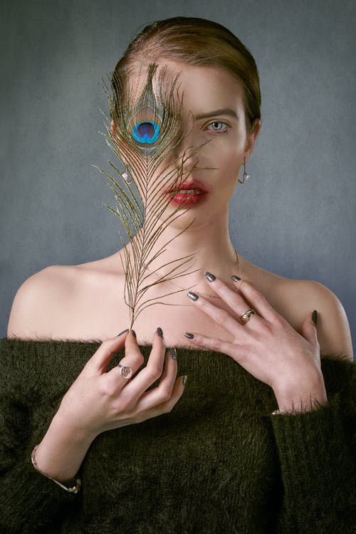 女模特用孔雀羽毛覆盖半张脸 · 免费素材图片