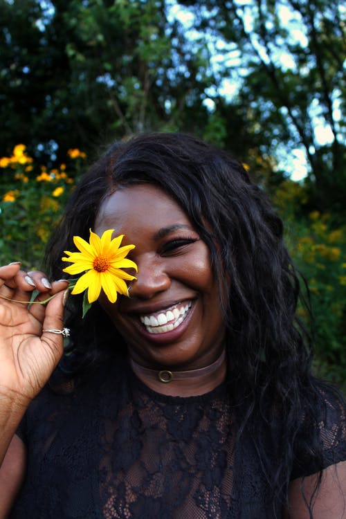 微笑的女士拿着黄色的花 · 免费素材图片