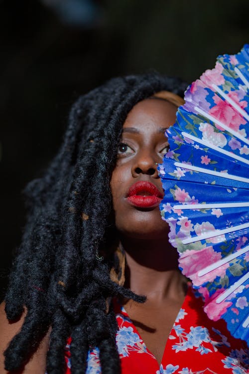 拿着蓝色和白色的花扇子的黑色针织帽的女人 · 免费素材图片