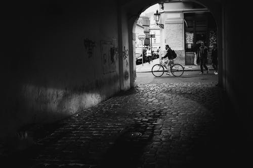 黑色外套骑自行车在灰色的混凝土路面上的男人 · 免费素材图片