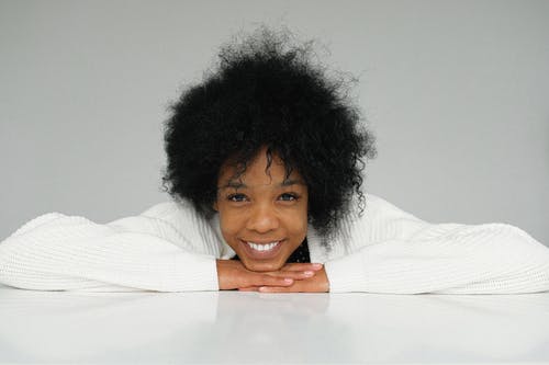 性格开朗的年轻黑人女性，靠在手上 · 免费素材图片