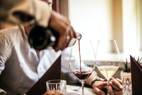 裁剪人倒红酒在餐厅的玻璃 · 免费素材图片