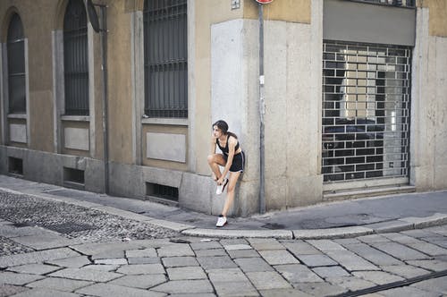 女运动员在城市训练期间绑鞋带 · 免费素材图片