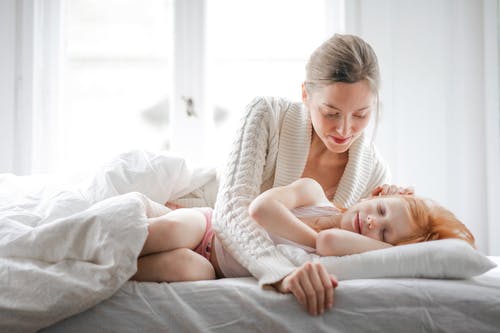 母亲爱抚着女儿，一起在家里的床上休息时 · 免费素材图片