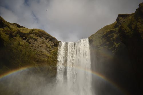 白云下的绿色和棕色山上的瀑布 · 免费素材图片