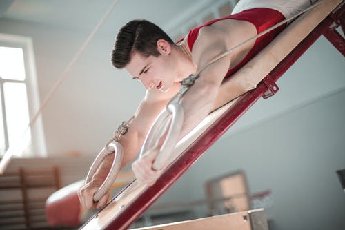 男体操运动员在体操环上练习的特写照片 · 免费素材图片