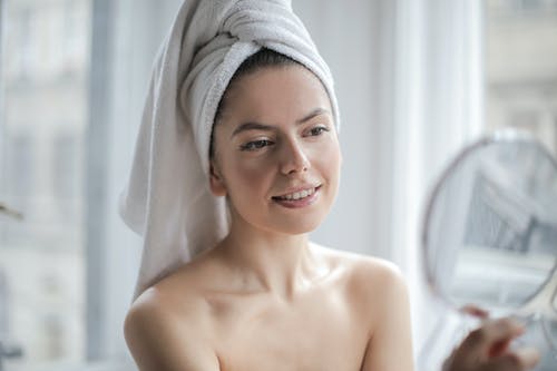 选择性聚焦肖像照片的微笑的女人，用毛巾擦着镜子的头上 · 免费素材图片