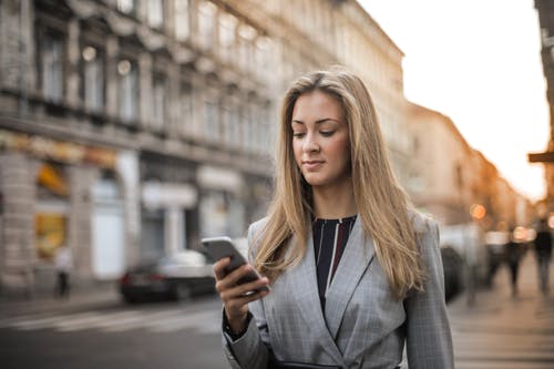 在灰色西装外套走路时发短信的女人的选择性焦点照片 · 免费素材图片