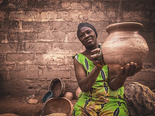 在当地的车间里显示工艺品陶器的非洲女人 · 免费素材图片