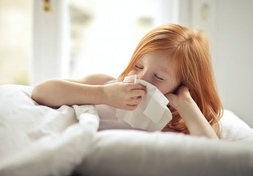 生病的青春期女孩在家里的床上休息时擦鼻涕 · 免费素材图片