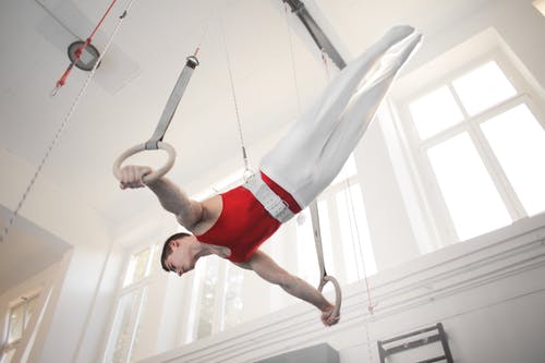男体操运动员在体操环上练习的照片 · 免费素材图片