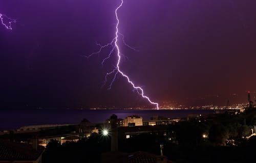 霹雳在沿海城市的紫色夜空中闪烁 · 免费素材图片