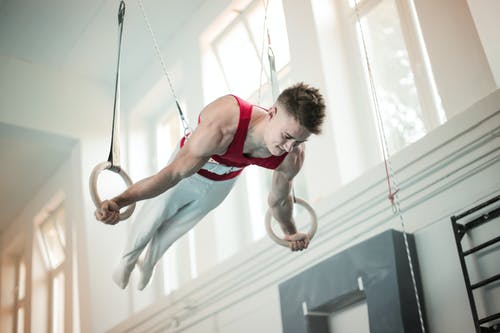 男体操运动员在体操环上练习的照片 · 免费素材图片