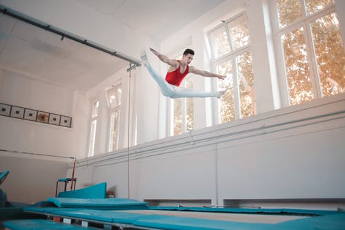 年轻的专业体操运动员，在蹦床上跳跃 · 免费素材图片