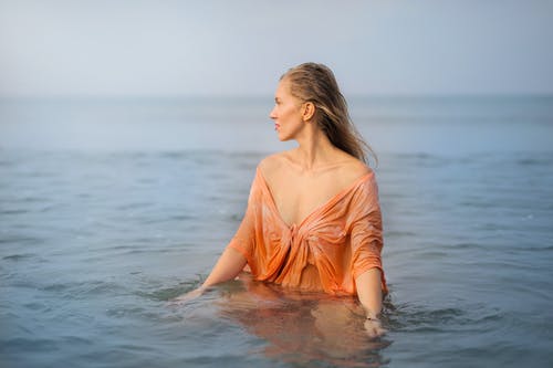 女人的照片在橙顶站在水的身体 · 免费素材图片