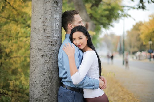 拥抱夫妇站在一棵树旁边的选择性焦点照片 · 免费素材图片