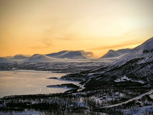 白雪皑皑的山区地形与日落时结冰的湖面 · 免费素材图片