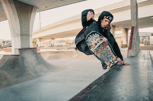 黑色连帽衫在滑板公园做滑板技巧的人的照片 · 免费素材图片