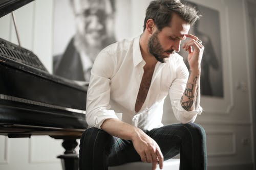 坐在钢琴上的戏剧性纹身男 · 免费素材图片