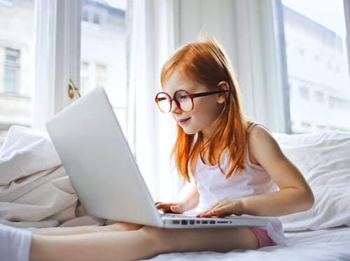 女孩的选择聚焦照片戴眼镜的女孩坐在床上，当使用膝上型计算机时 · 免费素材图片