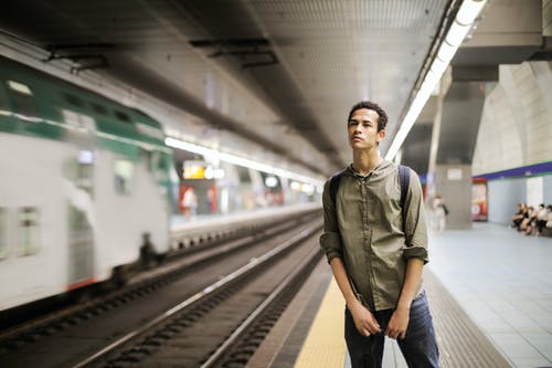 独自站在火车站月台的绿色衬衫的男人的照片 · 免费素材图片