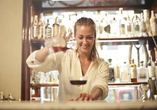 性格开朗的女酒保倒鸡尾酒在酒吧 · 免费素材图片