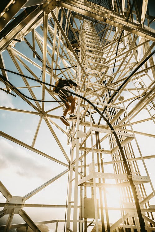 匿名人攀登金属塔在阳光灿烂的日子 · 免费素材图片