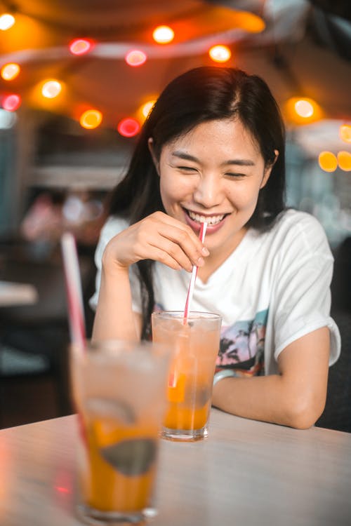 性格开朗的族裔女人喝美味的饮料，加冰在咖啡馆 · 免费素材图片