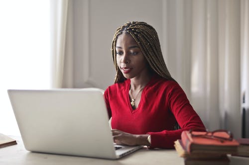 红顶女人坐在一张桌子时使用她的笔记本电脑的选择性焦点照片 · 免费素材图片