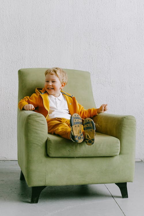 美满的男孩在客厅里的扶手椅上笑 · 免费素材图片