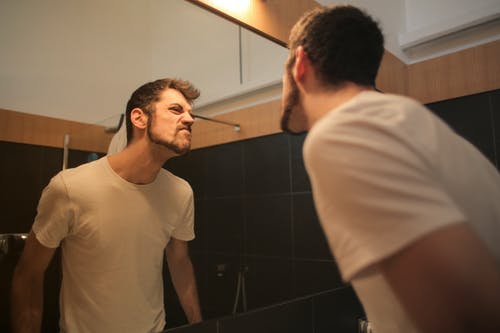 胡子拉man的年轻人看着镜子在浴室 · 免费素材图片