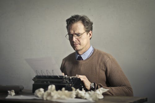 成人皱眉的男性作家在打字机上在家工作 · 免费素材图片