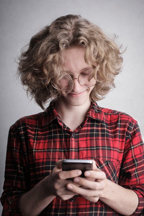 红色和黑色的格子衬衫发短信的微笑人的肖像照片 · 免费素材图片
