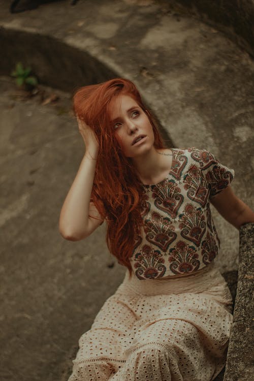 抬头坐在混凝土台阶上的女人的照片 · 免费素材图片