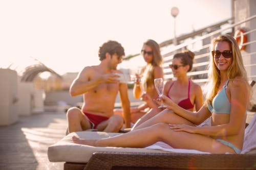 快乐的朋友，在阳光灿烂的夏天的一天一起在海滩上晒日光浴时喝美味的饮料 · 免费素材图片
