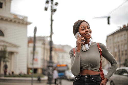 在电话上交谈时站立的灰色长袖衬衫和黑色牛仔牛仔裤的微笑妇女的选择性聚焦照片 · 免费素材图片