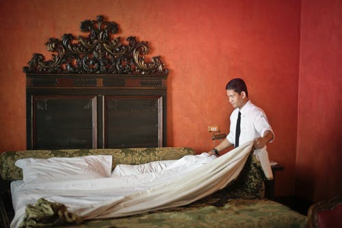 男仆在豪华酒店房间里铺床 · 免费素材图片