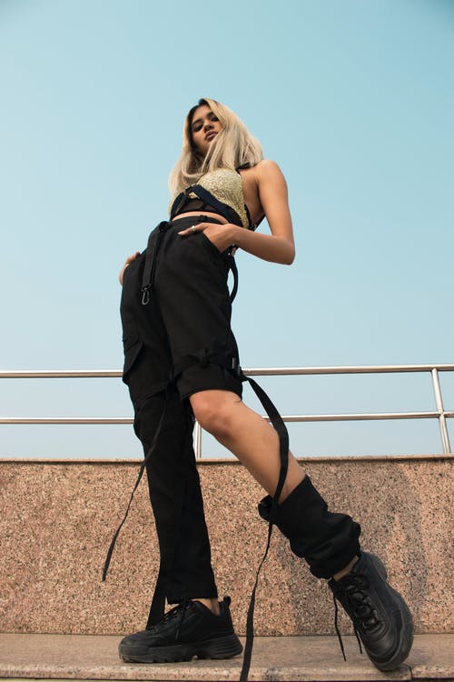 低角度的摆姿势的黑裤子和金顶往下看的女人的照片 · 免费素材图片