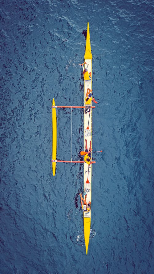 赛艇运动员在蓝色的水中的船上休息 · 免费素材图片