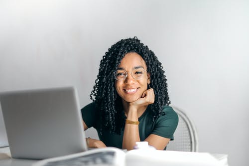坐在桌上的愉快的种族妇女与膝上型计算机 · 免费素材图片