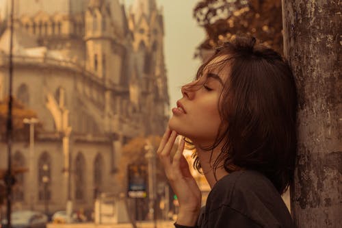 女人穿着黑色衬衫，倚着金属灯柱与她的眼睛合影的选择性焦点侧视图照片 · 免费素材图片