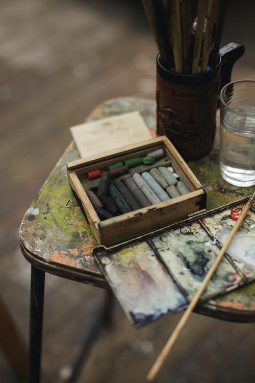 杯水旁边的木椅上的油漆刷 · 免费素材图片