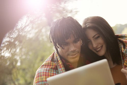 幸福的多民族夫妇在公园里使用平板电脑 · 免费素材图片