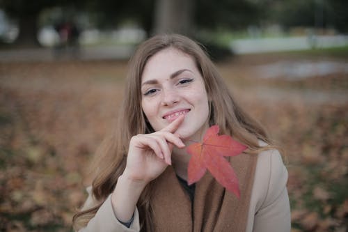 有红色叶子的愉快的妇女在城市公园在秋天 · 免费素材图片