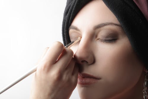 女人在她的眼皮上应用化妆品 · 免费素材图片