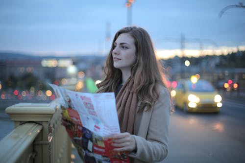 在城市的街道上看着别处的地图的年轻女子 · 免费素材图片