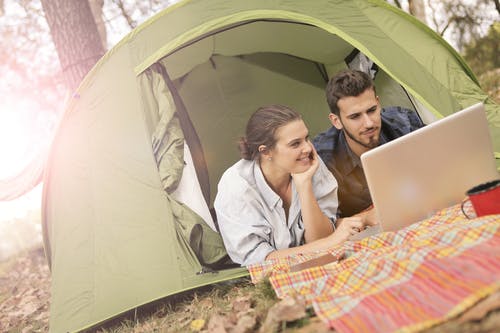 幸福的夫妇在帐篷中使用笔记本电脑 · 免费素材图片