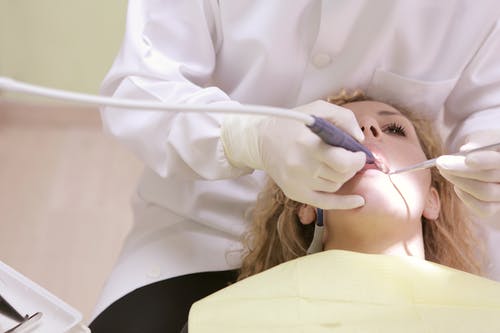 牙医在女人的牙齿上工作 · 免费素材图片