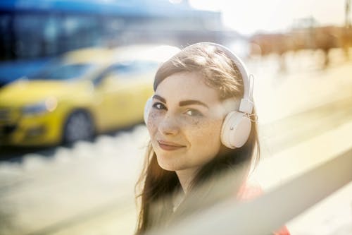 耳机的愉快的少妇听到在街道上的音乐的 · 免费素材图片